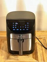 Front view of the Gourmia GAF798 air fryer showing the digital touch control panel illuminated with various cooking program icons and LCD timer display. The basket handle is visible with a stainless steel front panel.