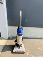 Front view of Hoover WindTunnel 2 vacuum upright on pavement showing full body, crevice tool attached, dust canister and base.