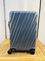 Front view showing diagonal ribbed front panel, four spinner wheels and base design