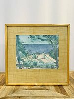 Coastal landscape painting in wooden frame with beige matting, showing buildings and ocean view.