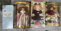 Four porcelain dolls in original boxes arranged side by side, showing full front view of each doll and packaging.