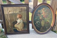 Both framed artworks shown side by side outdoors on wood railing - floral oval oil painting and child with bird print