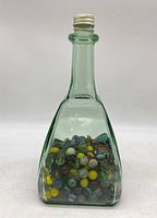 Front view of green tinted glass jar filled with assorted marbles