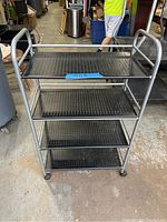 Front view of the metal cart showing four shelves and tubular frame