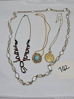 Full view of the four necklaces arranged together on a white surface showing their length and structure