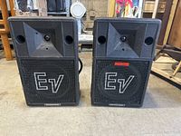 Front view of the pair of Electro-Voice Model 100s speakers showing the large speaker grille with 'EV' logo and tweeter horn.
