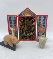 Front view of the retablo flanked by the animal sculpture and ceramic vase