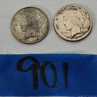 Two silver Peace Dollars obverse view showing profiles of Lady Liberty with dates visible.