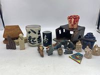 Group of Asian artsy items including stone animals, clay art, cups, wooden and pottery objects