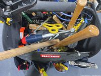 Top view of Craftsman black tool bag filled with assorted hand tools including wooden handled hammers, screwdrivers, scissors, and pliers.