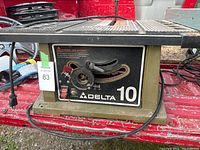 Side view of Delta 10 table saw with angle adjustment wheel, on/off switch, and power cord