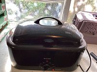 Front closed view of the black Bravetti electric roaster oven with temperature control dial on the front.