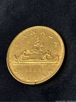 Obverse of the 1968 Canadian dollar coin showing the Voyageur design with two men paddling a canoe and the year 1968.