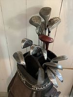 Close view of golf clubs heads in the Spalding golf bag showing irons and woods with one wood head cover.