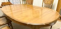Full view of the oval wooden dining table showing smooth polished surface and rounded edges.