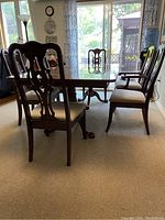 Dark wood dining table with chairs around, natural light from windows in background