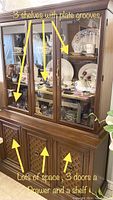 Front and side view of the vintage wooden display cabinet with glass upper doors showing plates inside, three shelves with plate grooves and lower section with three wooden doors