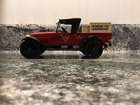 Side view of the red 1922 Studebaker Pickup diecast model with Canadian Tire box in back, showcasing the black convertible roof and wheels.
