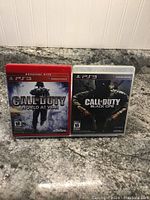Front covers of Call of Duty: World at War and Call of Duty: Black Ops PlayStation 3 games on granite counter.