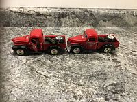 Side profile of two red diecast 1947 International pickup truck banks showing the spare tire in truck bed and overall condition.