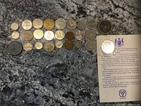 Photo showing an assortment of foreign coins, Chinese token, and Canadian coins and tokens arranged on a textured surface.