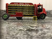 Side view of the red and white Danbury Mint 1938 Coca-Cola delivery truck showing 62 miniature Coca-Cola cases displayed on shelves, one broken front wheel visible.