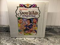 Photo of outer white box with colorful Snow White and Seven Dwarfs artwork and title.
