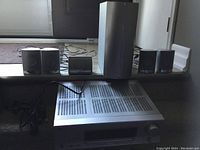 Entire surround sound system showing the receiver, powered subwoofer, and five small satellite speakers grouped on the stair step.