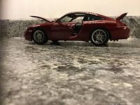 Side profile shot with driver door open showing exterior and interior details of burgundy Porsche 911 Targa scale model car.