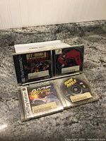 Four used PlayStation 1 game discs in jewel cases placed on a countertop, showing game titles and disc labels clearly.