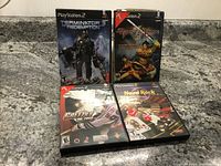 Four PlayStation 2 game cases arranged on a gray surface, showing front cover art for Terminator 3 Redemption, Backyard Wrestling 2, Gretzky NHL 2005, and Hard Rock Casino.