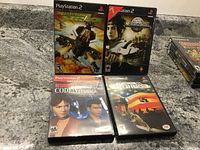 Four PlayStation 2 game cases laid out showing front covers including Desert Strike: Return to the Gulf, Atelier Iris: Eternal Mana, Resident Evil Code: Veronica X, and Conflict: Desert Storm.