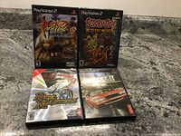 Photo showing four PS2 game cases placed on a granite countertop: Fire of Fighting, Scooby-Doo! Mystery Mayhem, Duel Masters, Driver: Parallel Lines.