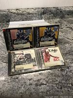Four PlayStation 1 game cases on a kitchen counter, including two NFL GameDay 2001 titles, one Brett Favre Pro Football, and one NBA Live 98.