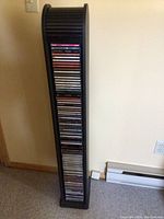 Tall black CD storage stand holding multiple CDs, showing height and design.