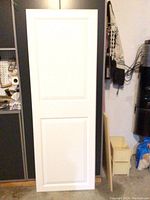 White door with two panel design and door hardware shown hanging upright.