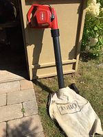 Side view of red Toro electric corded leaf blower with attached collection bag on grass.