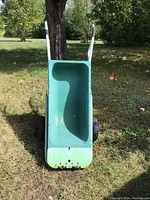 Front view of the green metal wheelbarrow showing basin and handles