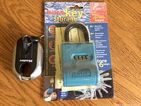 Photo of a new blue Shurlok combination lock box in original packaging and a black Master padlock with key attached on ring