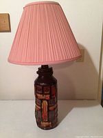 Photo of the ceramic table lamp showing the full lamp with textured geometric design base and pink pleated shade.
