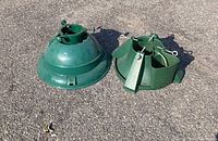 Photo of two green adjustable Christmas tree stands on pavement, showing top and side views.