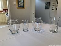 Photo showing all four clear glass vases on table with neutral background.