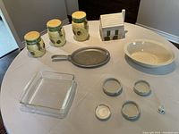Overview image of all items on table showing cookie jars, house shaped jar, bakeware and ashtrays