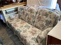 Floral patterned living room sofa with three seat cushions and floral upholstery in muted tones.