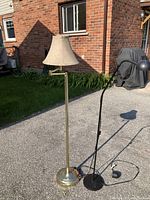 Two floor lamps on outdoor driveway showing both lamps fully in frame, one brass and one black IKEA.