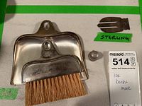 Brush and dustpan with 10K mark, thimble, and sterling silver clip arranged on a white surface with item tag.