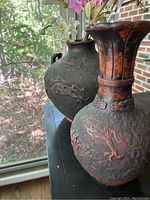 Overall view of two bronze-finish metal vases with dragon relief
