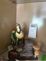 Full frontal view showing painted bird on log base with foliage and mushroom accents