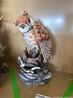 Full view of porcelain owl statue perched on a textured wood-like base, showing body and overall shape.
