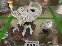 Two Boehm owl porcelain statues displayed together on glass shelf showing detailed feather patterns and snow-covered branches.